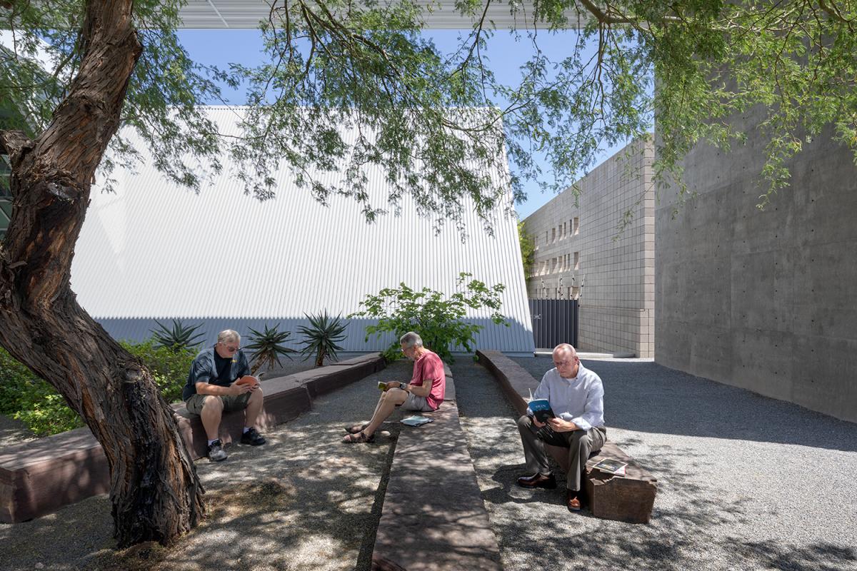 three docents sitting on outdoor benches reading poetry