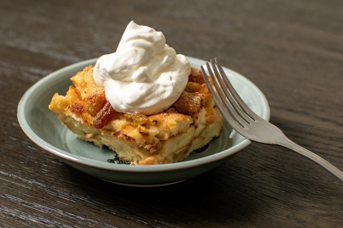 Bread pudding with whipped cream on a blue plate with a fork / photo by Tyler Espinoza