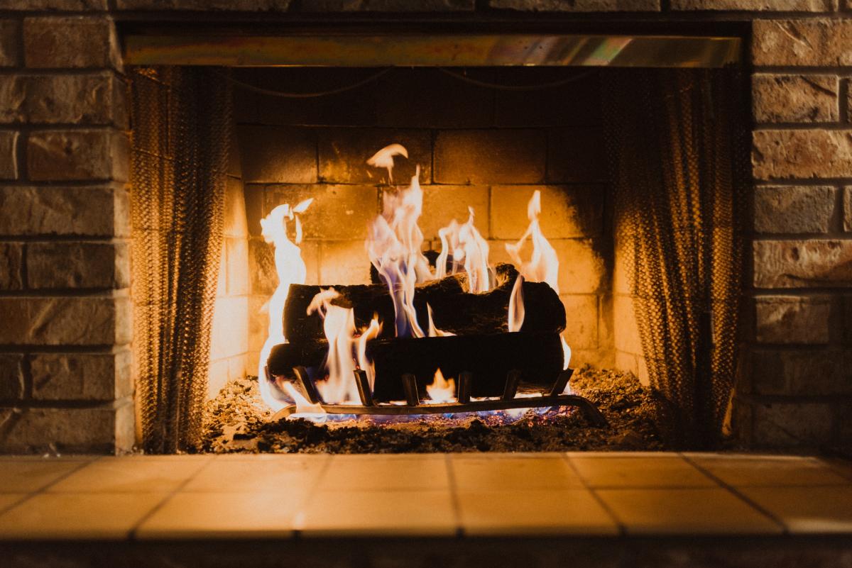 A fireplace with burning logs / photo by Hayden Scott