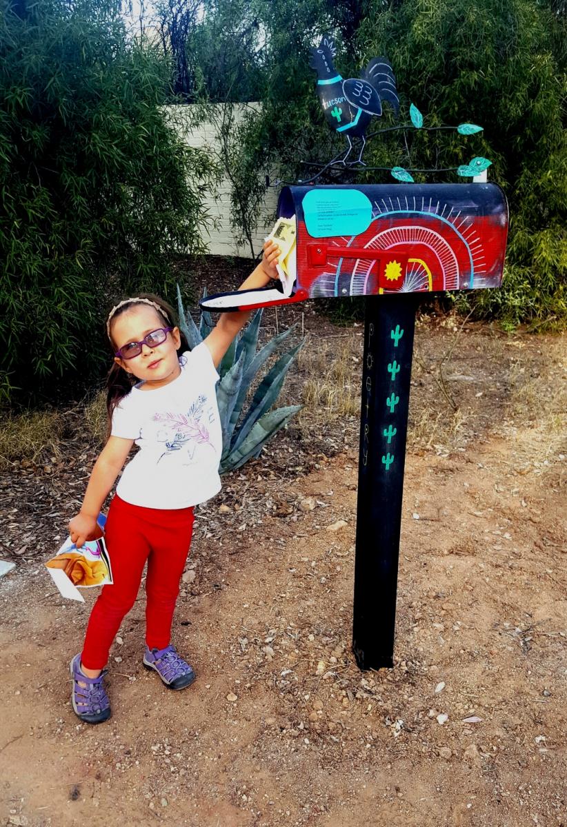 A child reaches up to the Poetry Mailbox to retrieve a poem.