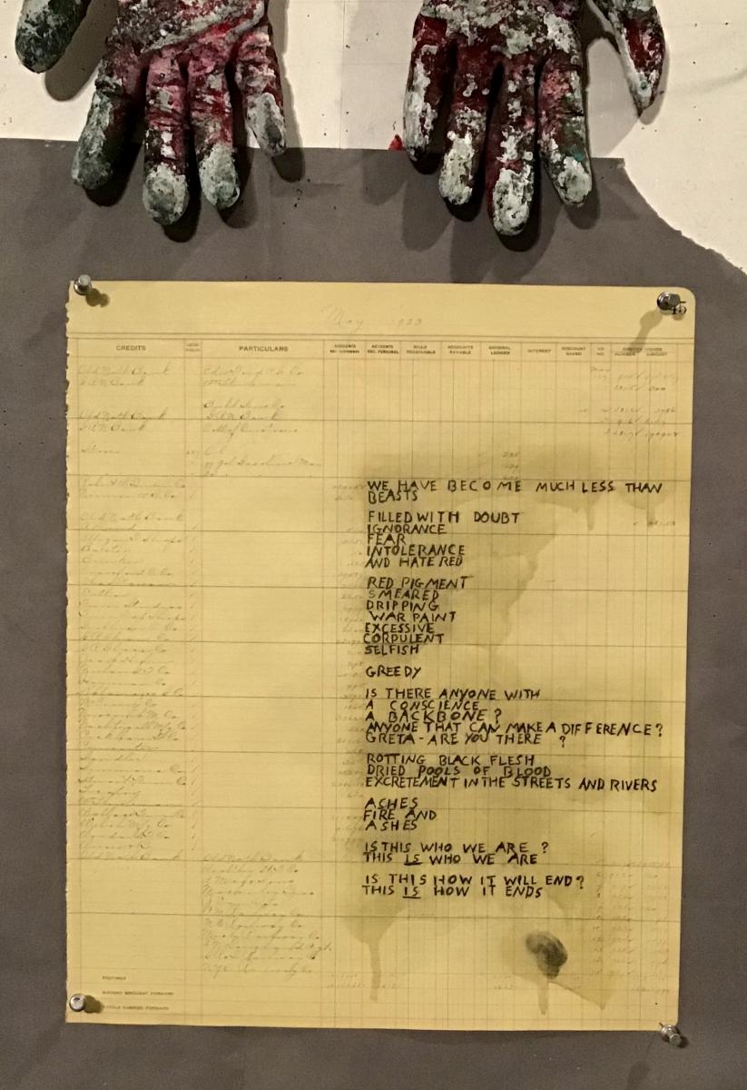 Photo of a poem on ledger paper, with two gloves at the top of the frame.