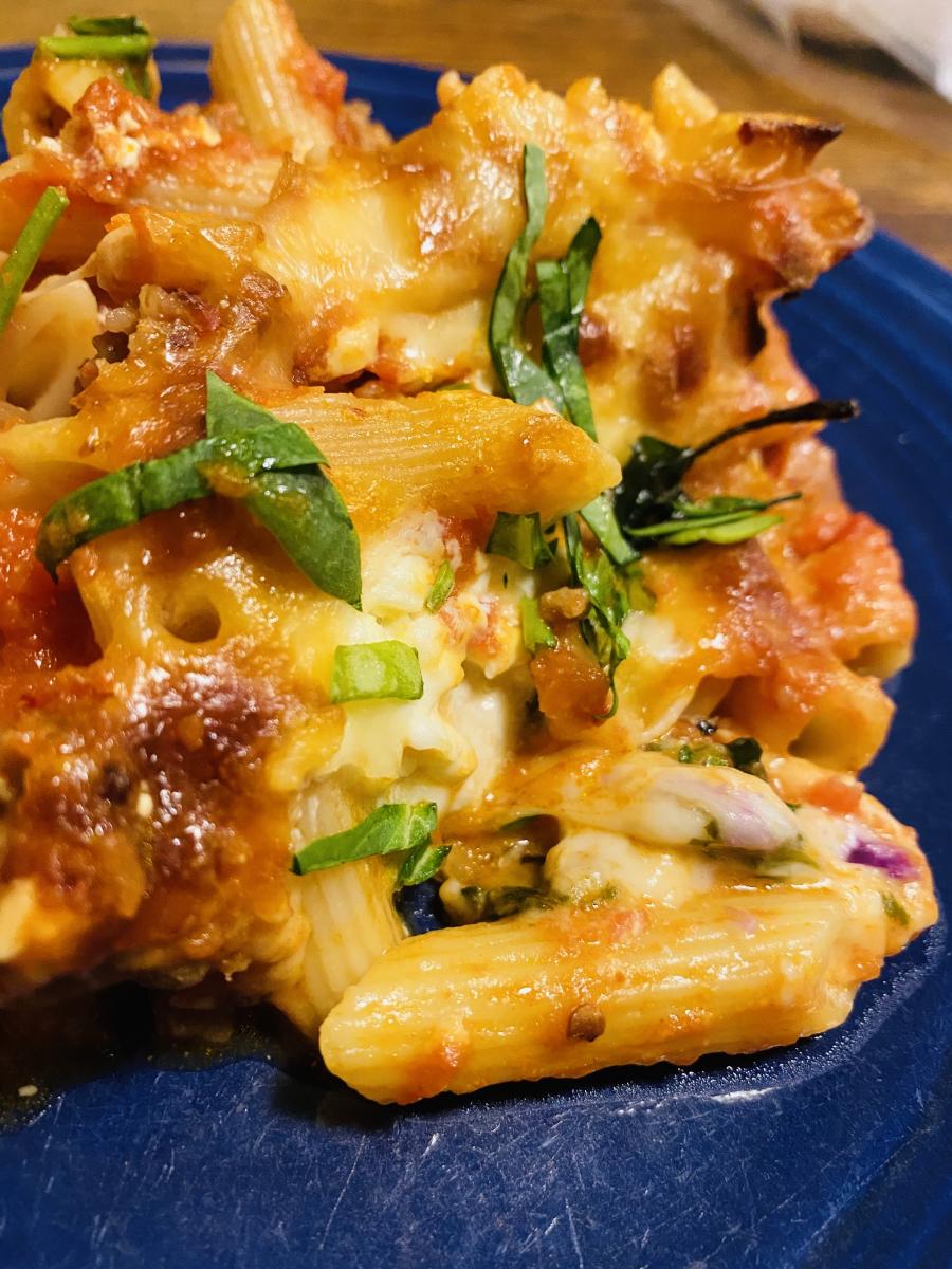 A closeup of baked ziti sprinkled with basil