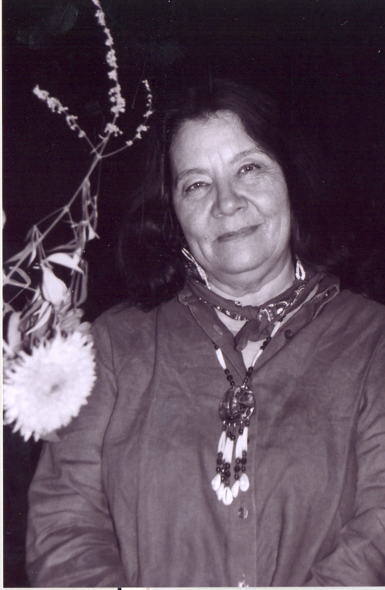 Leslie Marmon Silko stands in the desert at night, a flower near her right shoulder