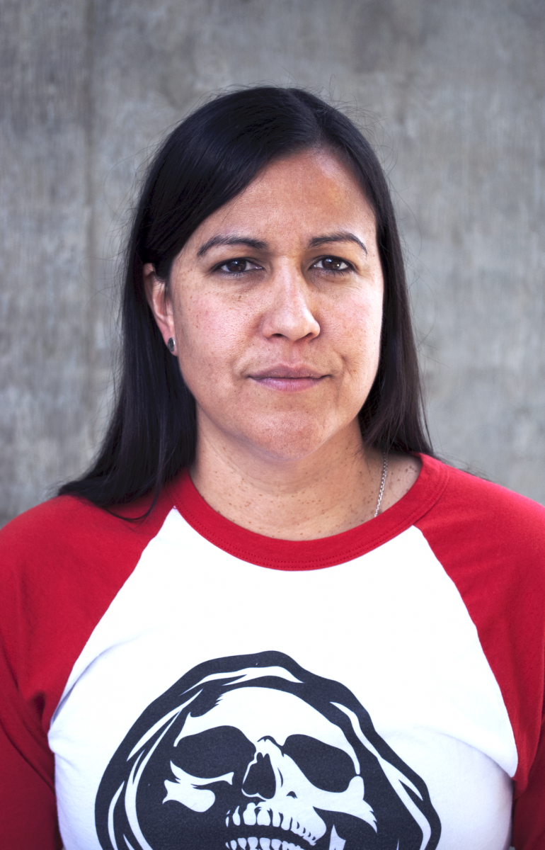 Natalie Diaz looks into the camera in front of a concrete wall at the Poetry Center