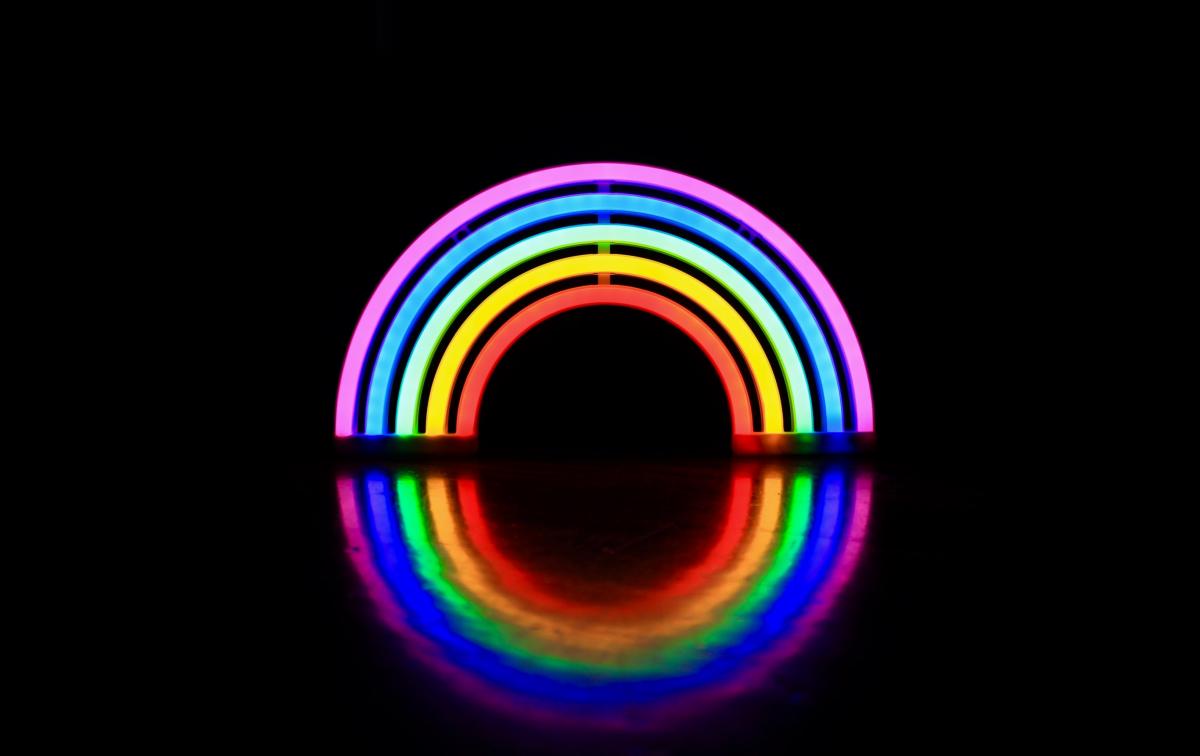 Rainbow light fixture against a black background / photo by Paola Franco