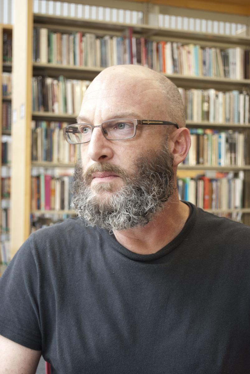 Richard Siken looks into the distance while sitting in the Poetry Center library