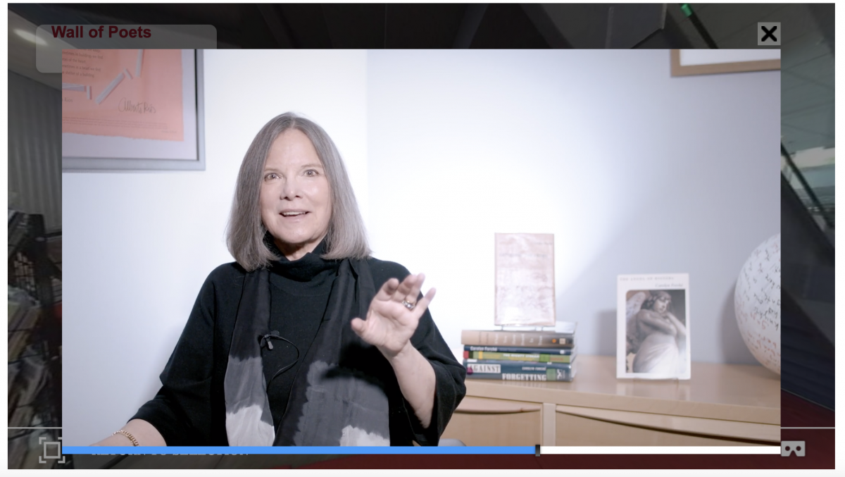 still of Carolyn Forché speaking from her home, holding a hand up to gesture