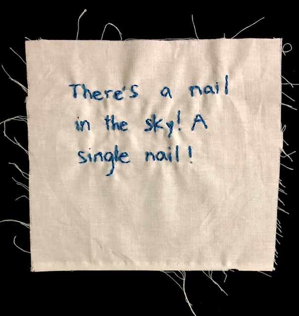 "There's a nail in the sky! A single nail!" stitched in blue thread on off-white canvas