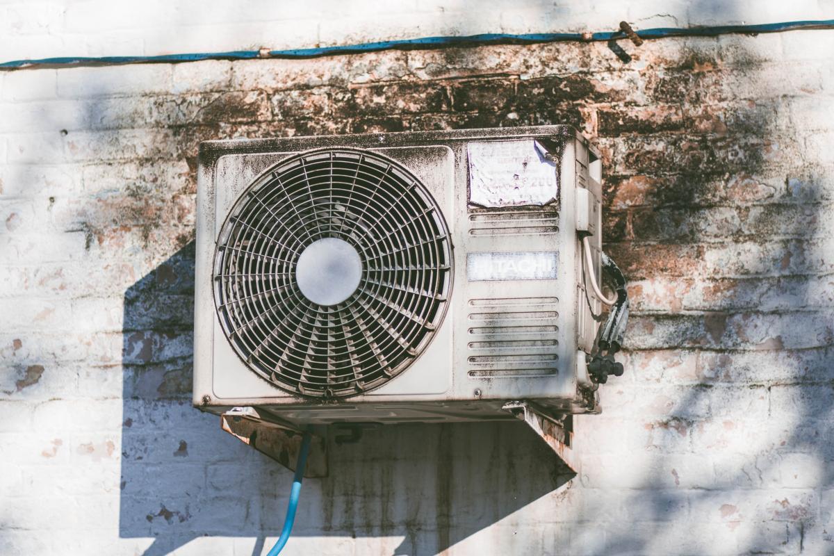 An outside air conditioning unit against a white brick wall