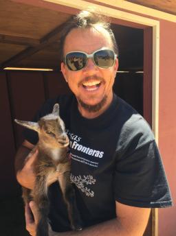 Poet TC Tolbert wears sunglasses and holds a baby goat 