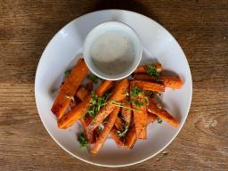 A plate of carrot fries and a small bowl of dipping sauce.