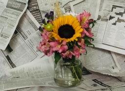 sunflower bouquet in a vase against a newspaper background