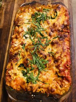 A tray of baked ziti sprinkled with basil