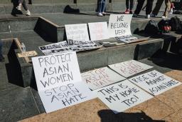 Anti-Asian hate protest signs laid out on grey steps. 
