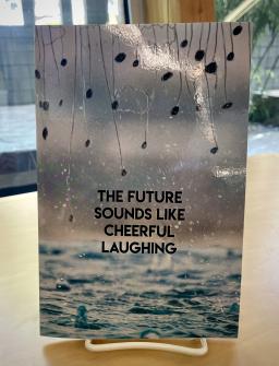 Book with rain and plants on it, with the title, "The Future Sounds Like Cheerful Laughing"