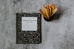 Marble notebook and container of pencils against a gray background