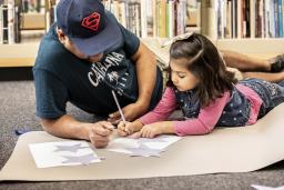 An adult and child work on a writing activity together