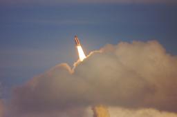 a space shuttle launches with smoke and clouds surrounding it as it ascends