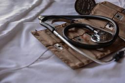 Stethoscope on bag with medical tools, laying on white sheet
