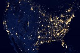 The United States as seen from orbit at night: a dark outline of the continent studded with lights