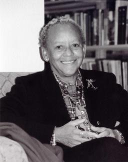 The poet sits in front of a bookshelf in a https://poetry.arizona.edu/sites/poetry.arizona.edu/files/nikki_giovanni_2-26-2006_by_christine_krikliwy.jpgblack blazer