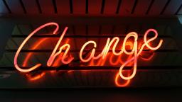 Neon sign reading "Change" in orange text, photo by Ross Findon