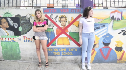 Two people stand against a wall with murals / still from CHIFLADA by Monica McClure  