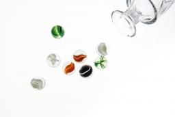 Marbles and glass jar on white background