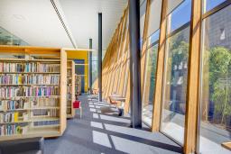 Book shelves and large windows in the Poetry Center library with view of the outdoor bamboo garden.