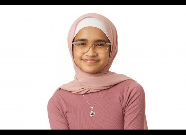 Smiling person wearing a pink sweater, pink hijab, and pink glasses
