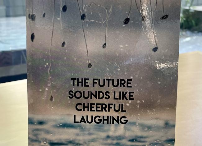 Book with rain and plants on it, with the title, "The Future Sounds Like Cheerful Laughing"