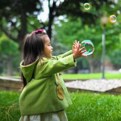 A small child holds a bubble in the park