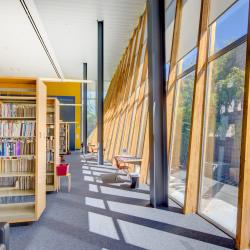 Book shelves and large windows in the Poetry Center library with view of the outdoor bamboo garden.